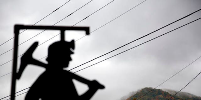 In this Oct. 16, 2014 file photo, fog hovers over a mountaintop as a cutout depicting a coal miner stands at a memorial to local miners killed on the job in Cumberland, Ky.