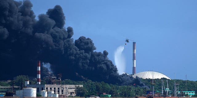 A helicopter dumps water over the Matanzas Supertanker Base as firefighters try to quell a blaze, which began during a thunderstorm the night before, in Matanzas, Cuba, Aug. 6, 2022. (AP Photo/Ramon Espinosa)