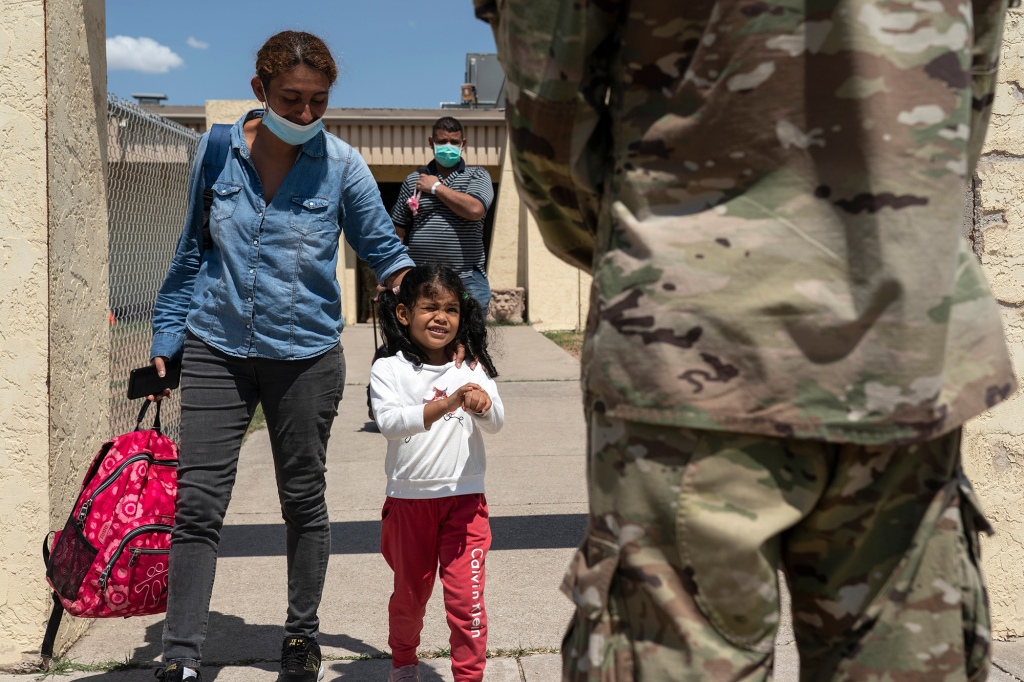 Migrants leave the building of Border Humanitarian Coalition, a volunteer organization which supports migrants to get to their final destinations, to get on the bus to New York City which is chartered by Texas Governor’s Office, as a National Guard officer stands to send them off in Del Rio, Texas on August 12, 2022.