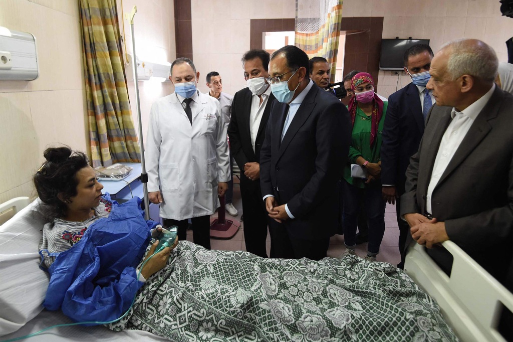 Prime Minister Mostafa Madbouli (C) and Health Minister Khaled Abdel-Ghaffar (C-L) visiting an injured woman at a hospital following the Abu Sifin church fire