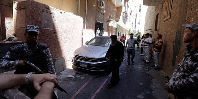 People and policemen stand near the scene where a deadly fire broke out at the Abu Sifin church in Cairo's Imbaba neighborhood on Sunday.