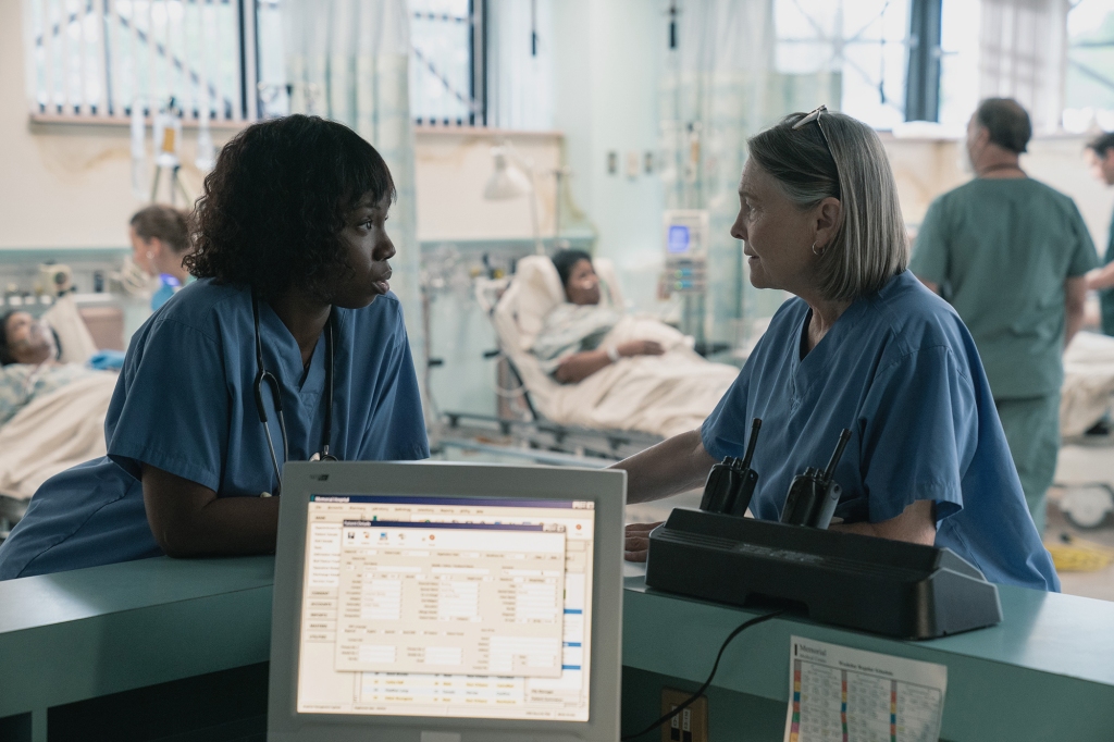 Adepero Oduye as ICU nurse manager Karen Wynn and Cherry Jones as nursing director Susan Mulderick. They're talking to each other at the nurses' station in the emergency room and they're both wearing blue hospital scrubs.