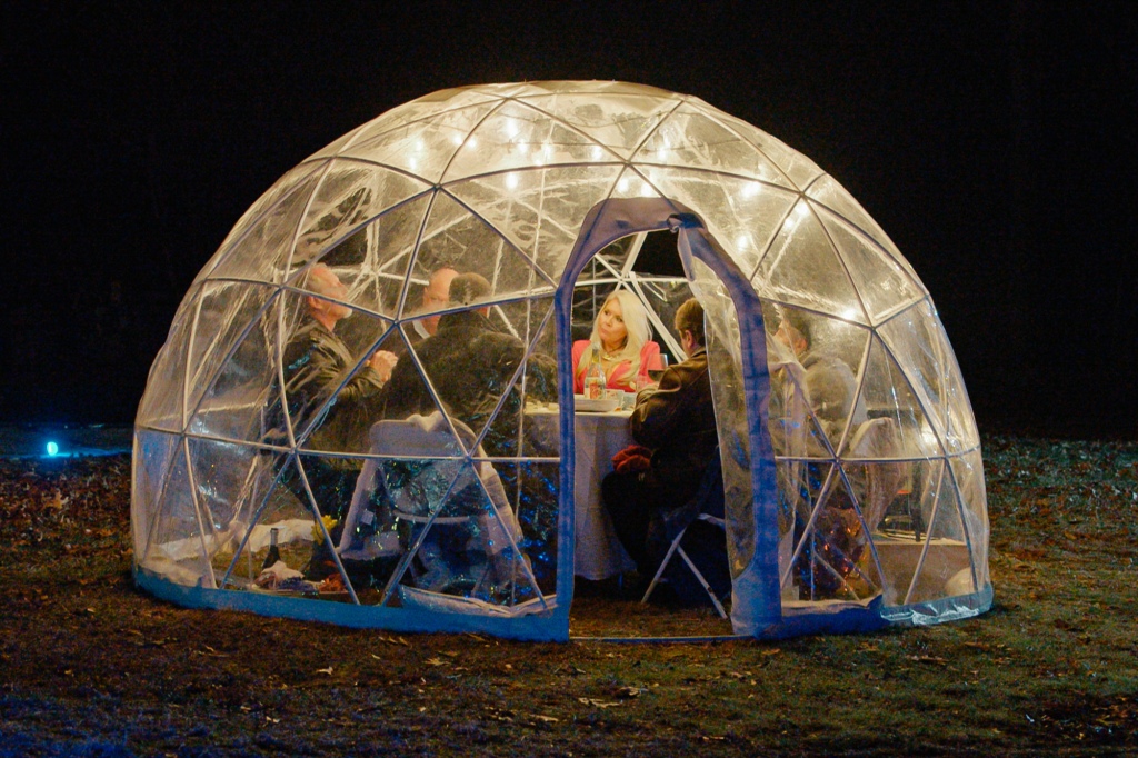 The cast of Five Guys a Week Episode 4 dining outdoors in a plastic bubble shelter.