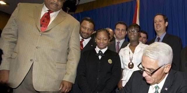 Denisha Merriweather, center, looks on as Florida Gov. Charlie Crist signs into law an expansion of the tax credit scholarship.