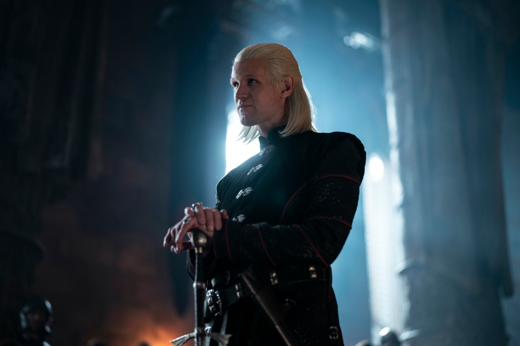 Matt Smith as Prince Daemon Targaryen in "House of the Dragon." He stands in a room with his hands on a sword stuck in the ground. 