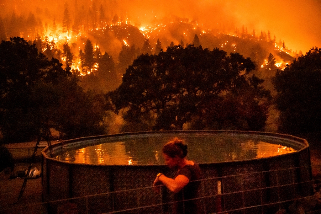 A woman and a pool in front of a raging wildfire
