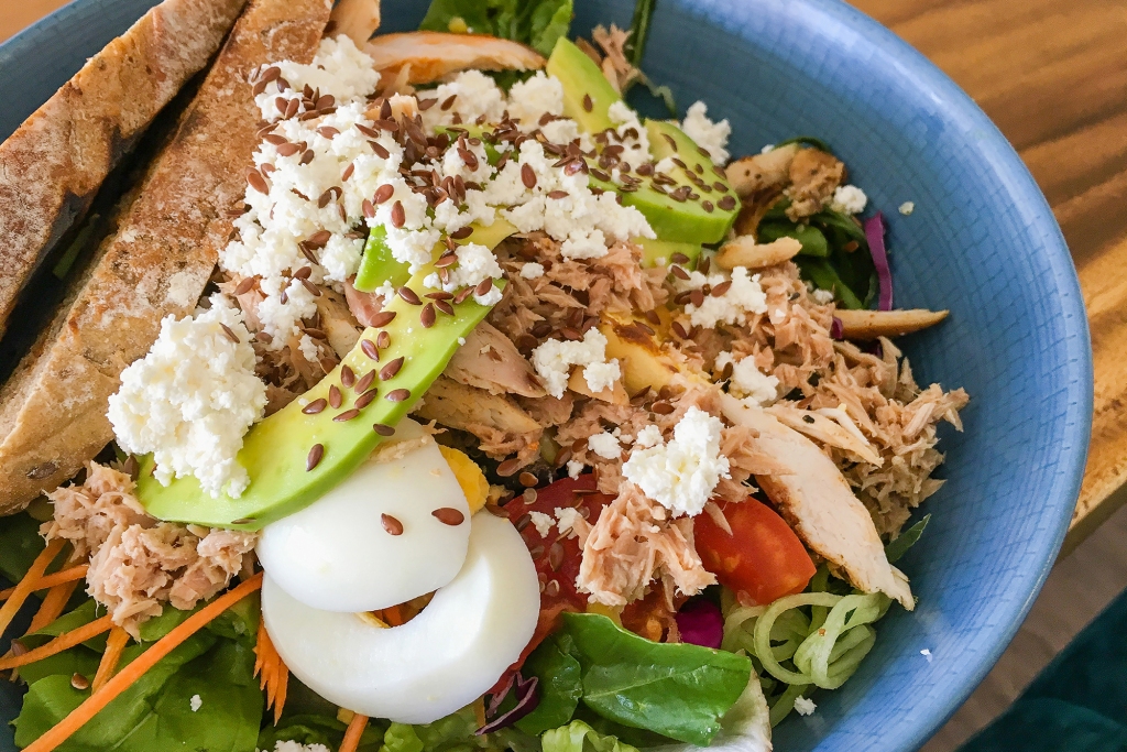 A chicken shawarma salad with toasted bread, feta cheese, and leaf vegetables.