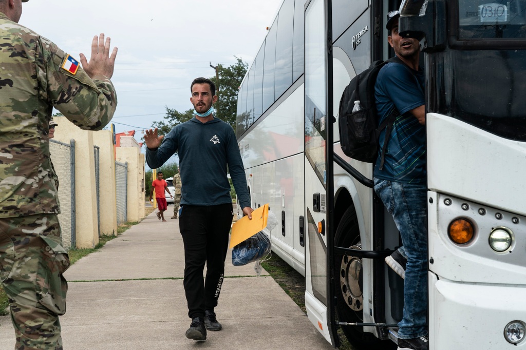 Migrants get on to the bus to Washington D.C. which is chartered by Texas Governor’s Office, as a National Guard officer sends them off in Del Rio, Texas on August 11, 2022.