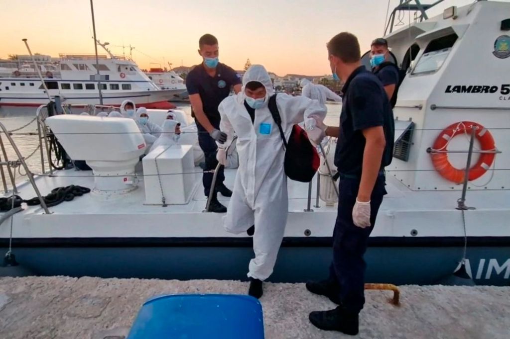 A migrant arrives and is helped by rescuers on a port on the southeastern Aegean Sea island of Kos on August 10, 2022. 