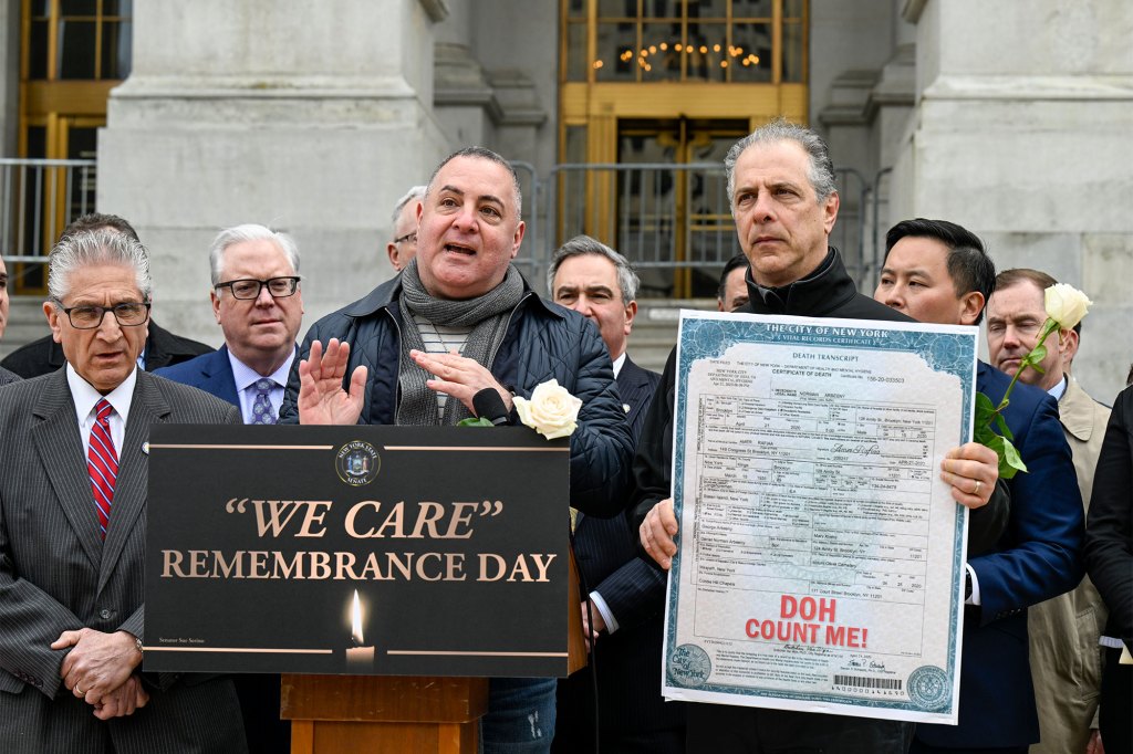 Brothers Peter, left, and Daniel Arbeeny of Brooklyn, hold a death certificate of their father as they stand with Lawmakers to honor the lives of New York residents who died in nursing homes during the COVID-19 pandemic.