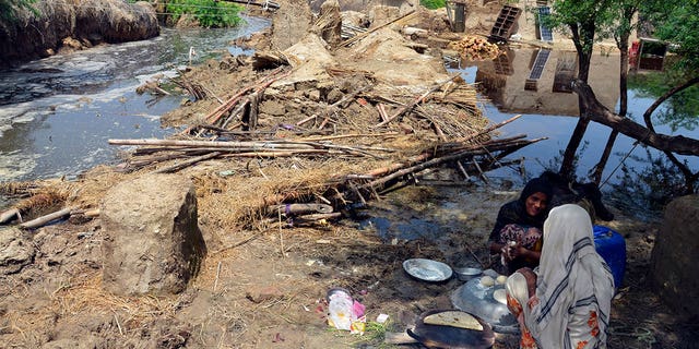 Pakistani women make bread near their damaged home surrounded by floodwaters, in Jaffarabad, a district of Pakistan's southwestern Baluchistan province, Sunday, Aug. 28, 2022. Army troops are being deployed in Pakistan's flood affected area for urgent rescue and relief work as flash floods triggered after heavy monsoon rains across most part of the country lashed many districts in all four provinces. 