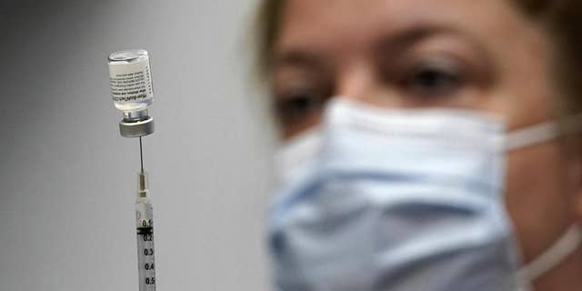 In this March 2, 2021, file photo, a pharmacy technician loads a syringe with Pfizer's COVID-19 vaccine at the Portland Expo in Portland, Maine. 