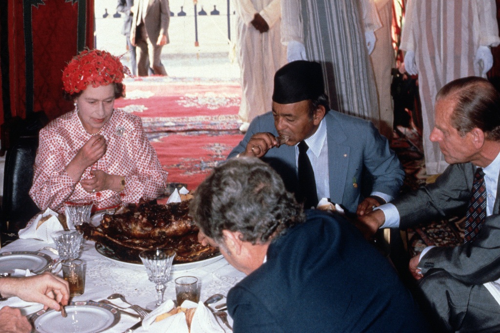 Queen Elizabeth II,  Prince Philip, Duke of Edinburgh and King Hassan ll eat with their hands as they attend a feast in the desert on October 27, 1980 in Morocco.