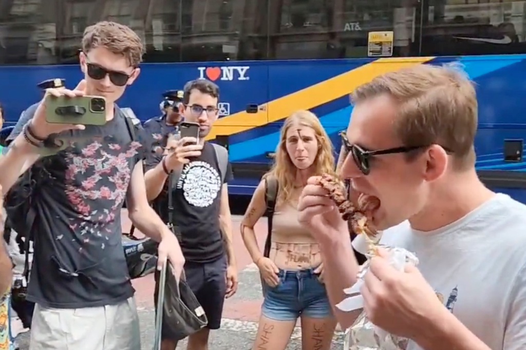 The man licks his food in front of the protestors.