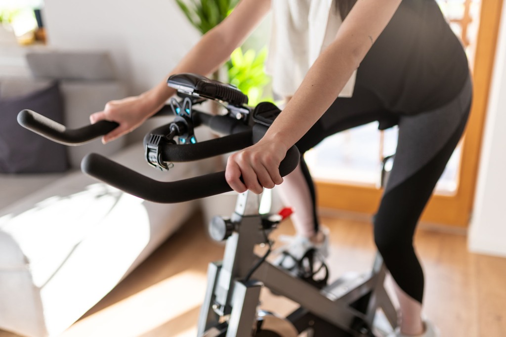 Low section shot of a woman in sportswear exercising on an exercise bike at home.