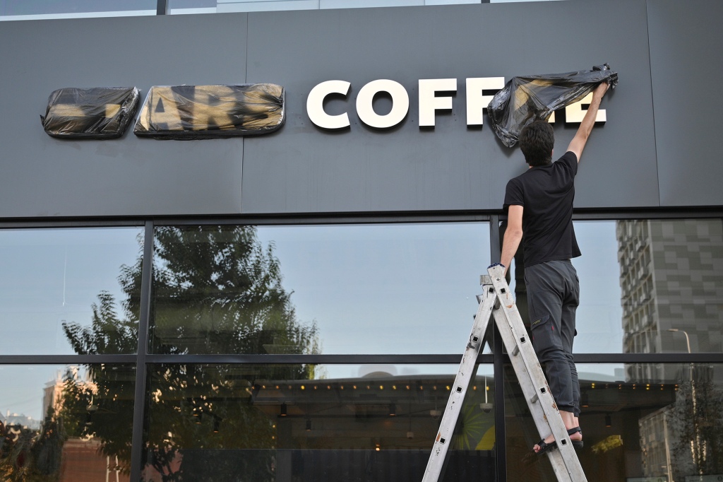 A worker removes a cover from the name of a newly opened Stars Coffee.