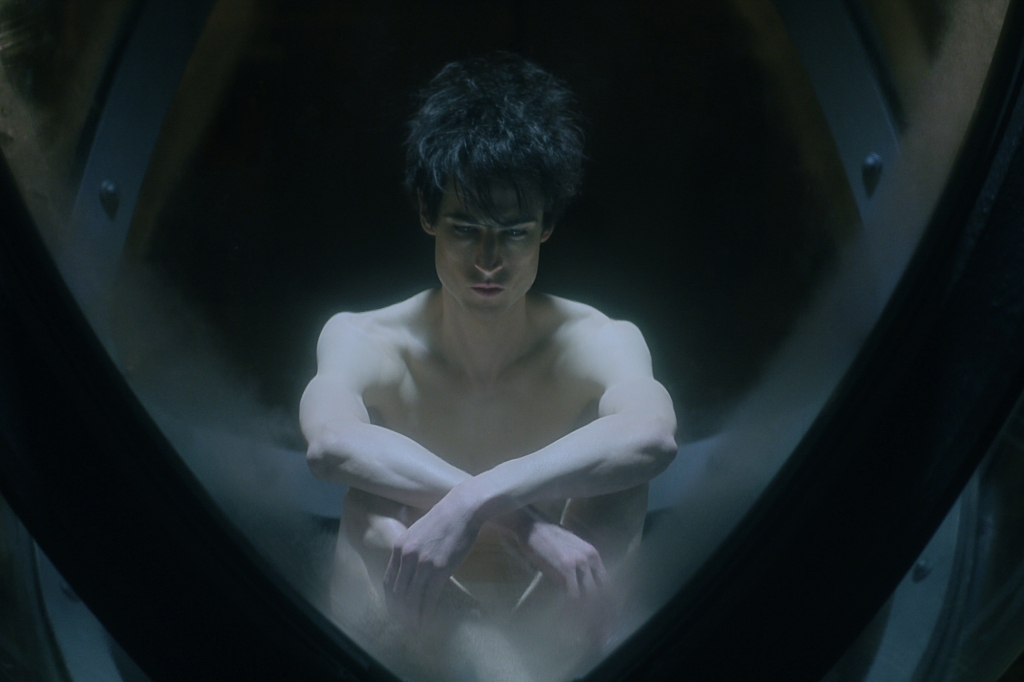 Tom Sturridge sits nude in a glass bubble. 