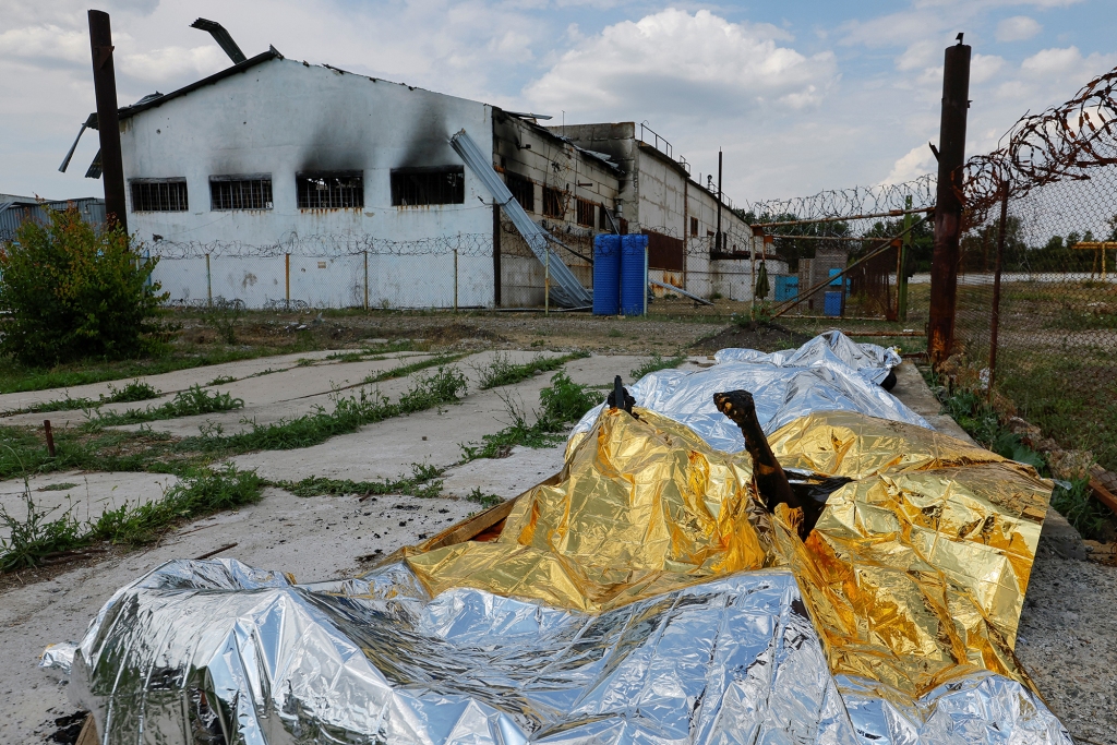 Burnt bodies of detainees lie covered following the shelling at a pre-trial detention center in the course of Ukraine-Russia conflict, in the settlement of Olenivka in the Donetsk Region, Ukraine May 29, 2022.