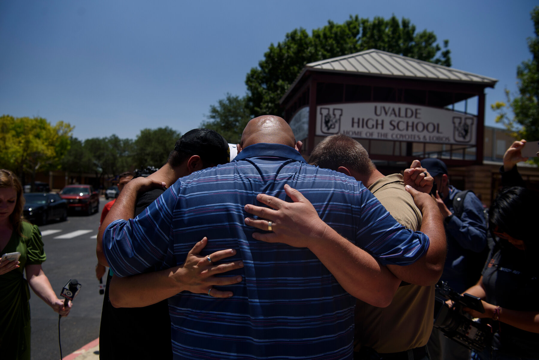 A group of people embraced after a news conference at Uvalde High School.