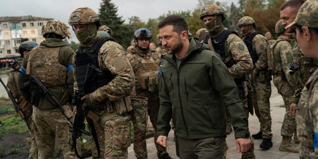 Surrounded by soldiers the Ukrainian President Volodymyr Zelenskyy attends a national flag-raising ceremony in the freed Izium, Ukraine, Wednesday, Sept. 14, 2022.