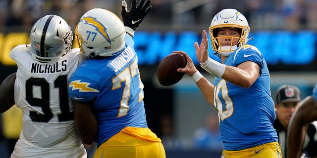 Los Angeles Chargers quarterback Justin Herbert passes as Las Vegas Raiders apply pressure in Inglewood, California, Sept. 11, 2022.