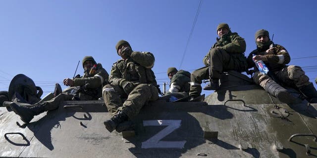 Russian military and pro-Russian separatists keep watch as civilians are being evacuated along humanitarian corridors from the Ukrainian city of Mariupol on March 24, 2022.