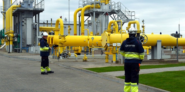 FILE: Workers stand near the pipelines during an opening ceremony of the Baltic Pipe in Budno, Poland, Tuesday, Sept. 27, 2022.