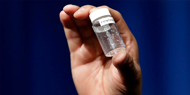 A reporter holds up a jar of fentanyl at DEA Headquarters in Arlington, Va., June 6, 2017. 