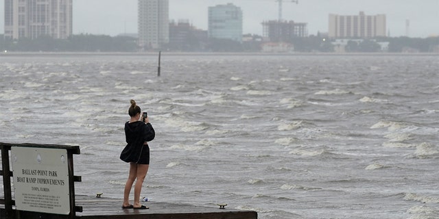 A woman takes photos of the surf on Tampa Bay ahead of Hurricane Ian, Wednesday, Sept. 28, 2022, in Tampa, Fla. 