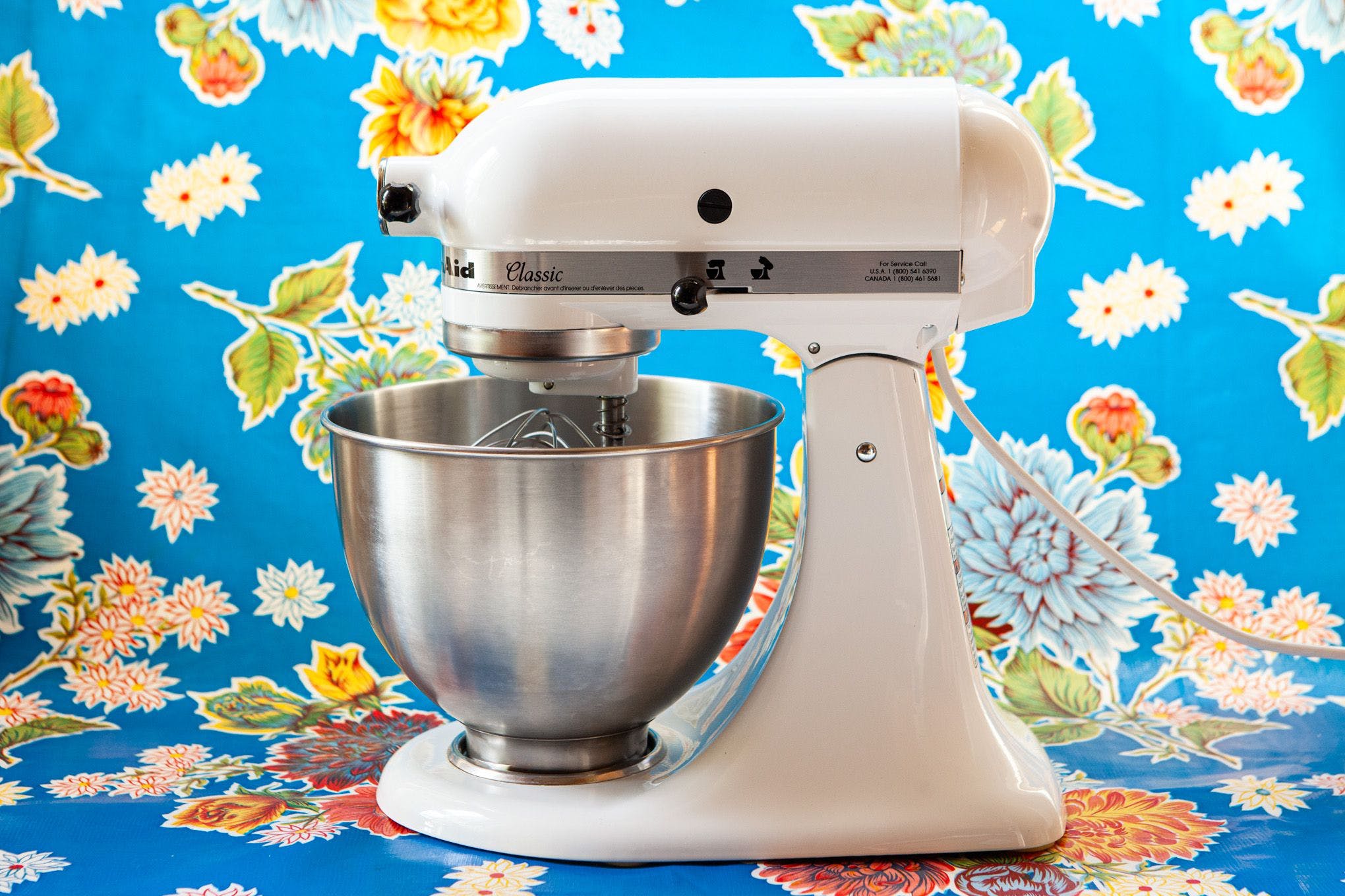 Photo of a KitchenAid stand mixer, in front of a blue floral background.