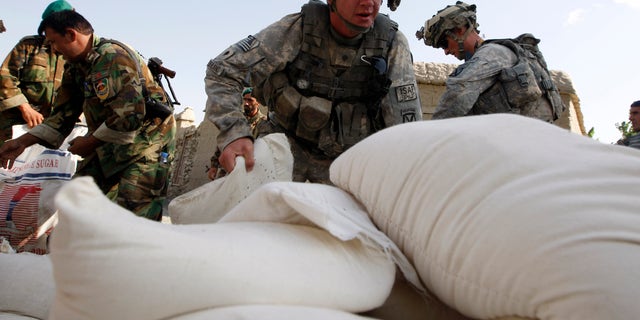 U.S. soldiers from 2nd Platoon, Alpha Company, 32nd Infantry Regiment unload bags of humanitarian aid at the village of Doment in Afghanistan's Kunar province Aug. 16, 2009.   