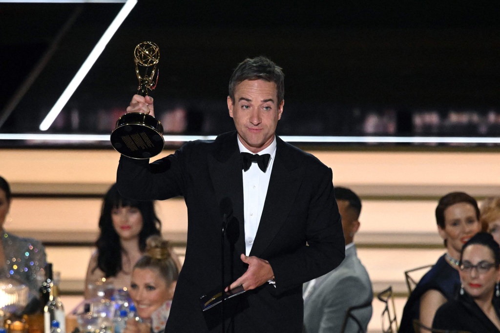 Matthew Macfadyen holding an Emmy onstage.