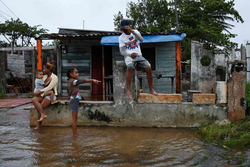 A family is seen outside their flooded home in Batabano, Cuba, on Sept. 27, 2022.