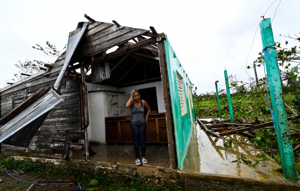 A woman stands in front of her house that was destroyed by Hurricane Ian, in San Juan y Martinez, Cuba, on Sept. 27, 2022. 