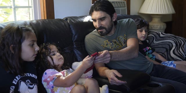 Mohammad Walizada, center right, who fled Afghanistan with his family, sits with three of his children, from the left, Zahra, 10, Hasnat, 3, and Mohammad Ibrahim, 7, Thursday, Sept. 15, 2022, at their home, in Epping, N.H. Since the U.S. military’s withdrawal from Kabul last year, the Sponsor Circle Program for Afghans has helped over 600 Afghans restart their lives in their communities. Now the Biden administration is preparing to turn the experiment into a private-sponsorship program for refugees admitted through the U.S. Refugee Admissions Program and is asking organizations to team up with it to launch a pilot program by the end of 2022. (AP Photo/Steven Senne)