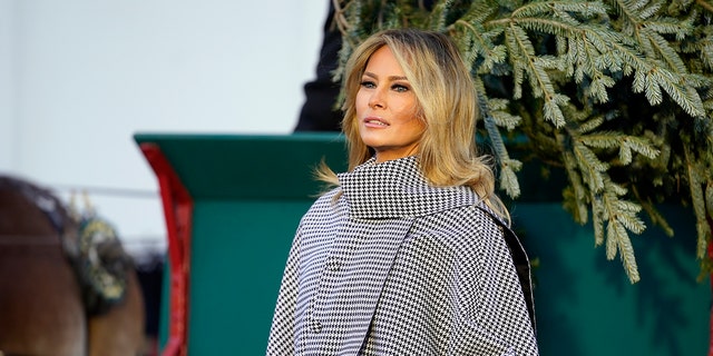 First lady Melania Trump stands next to the 2020 official White House Christmas tree as it is presented on the North Portico of the White House Nov. 23, 2020, in Washington. 