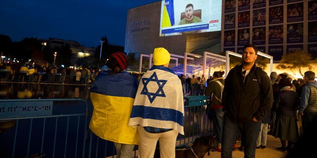 People gather in Habima Square in Tel Aviv, Israel, to watch Ukrainian President Volodymyr Zelenskyy in a video address to the Knesset, Israel's parliament.