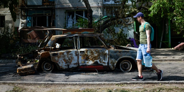 FILE - A man carries water in front of an apartment building damaged in an overnight missile strike, in Sloviansk, Ukraine, May 31, 2022. The U.S. intelligence community has launched a review of how it judges foreign governments’ will and ability to fight. American spy agencies underestimated Ukraine's will to fight while overestimating Russia's ability to overrun the country, even as it accurately predicted Russian President Vladimir Putin would order an invasion. (AP Photo/Francisco Seco, File)