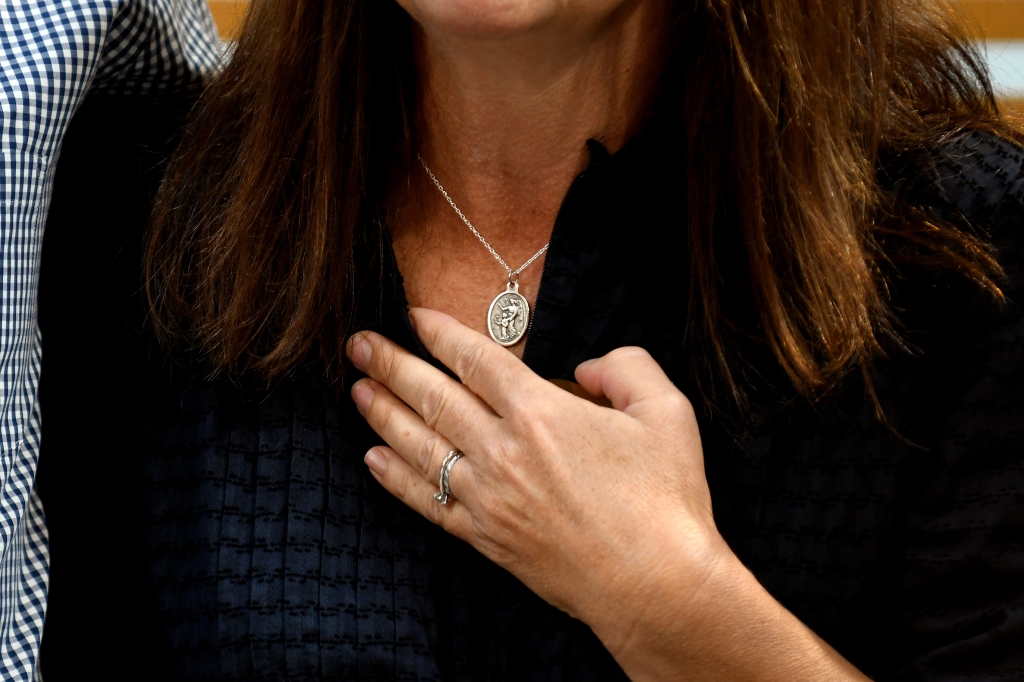 Sally Glass wears a Jesus and Mary pendant during a news conference