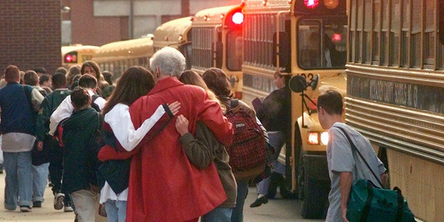 Students arriving at Heath High School in West Paducah, Ky., embrace an unidentified adult on Tuesday, Dec. 2, 1997, after student Michael Carneal opened fire at the school the day before, leaving three students dead and five wounded. 