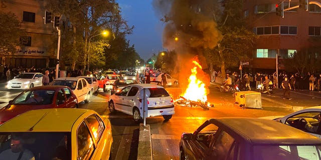 A police motorcycle burns during a protest over the death of a young woman who had been detained for violating the country's conservative dress code, in downtown Tehran, Iran, Sept. 19, 2022.