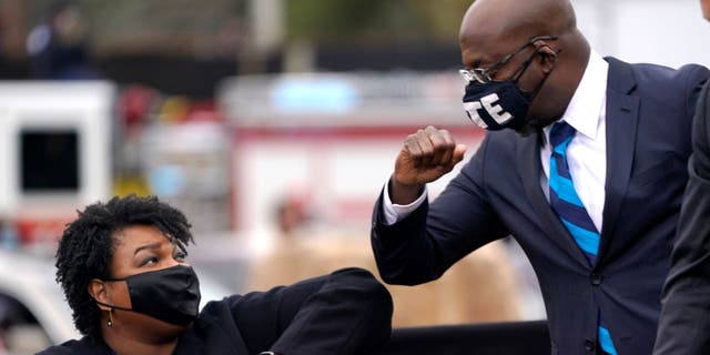 U.S. Democratic Senate candidate Raphael Warnock, right, bumps elbows with Stacey Abrams during a campaign rally.