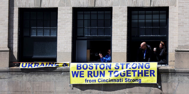 Spectators look out of their window during the 126th Boston Marathon on April 18, 2022, in Boston.