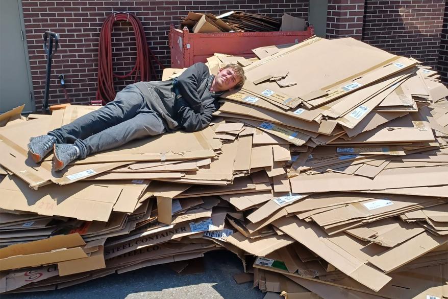 Ashton Gilbert is seen lying down on an honest day’s work of cardboard recycling.