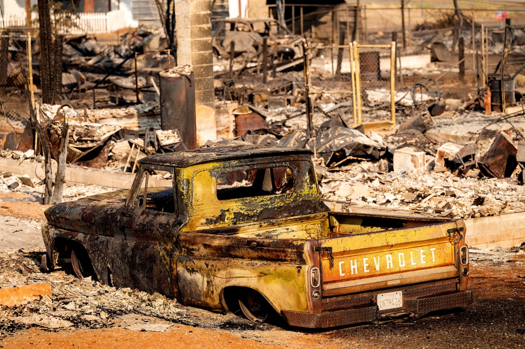 A scorched pickup truck sits in front of a Wakefield Avenue home destroyed by the Mill Fire on Sept. 3, 2022, in Weed, Calif.