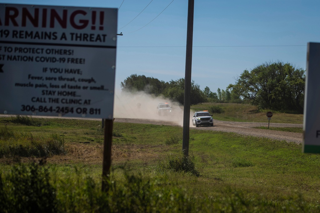 Canadian law enforcement personnel rush to surround a home on the James Smith Cree First Nation reservation in Saskatchewan.