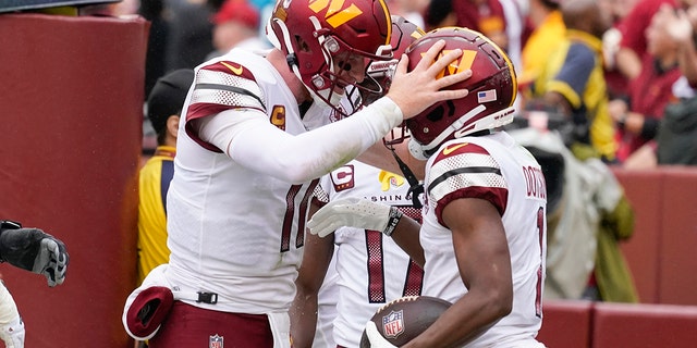 Washington Commanders quarterback Carson Wentz, #11, celebrates with wide receiver Jahan Dotson, #1, after scoring a touchdown against the Jacksonville Jaguars in the first half of an NFL football game, Sunday, Sept. 11, 2022, in Landover, Maryland.