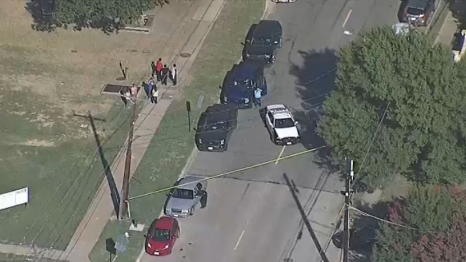 a police car and bystanders at scene of shooting