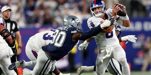 Daniel Jones (8) of the New York Giants scrambles against DeMarcus Lawrence of the Dallas Cowboys during the second quarter at MetLife Stadium on Sept. 26, 2022, in East Rutherford, New Jersey.