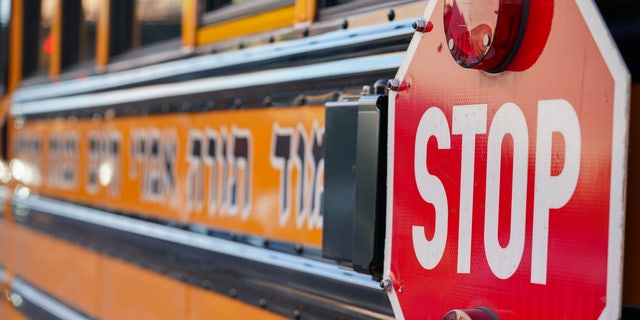 A yellow school bus is seen parked outside a school. 